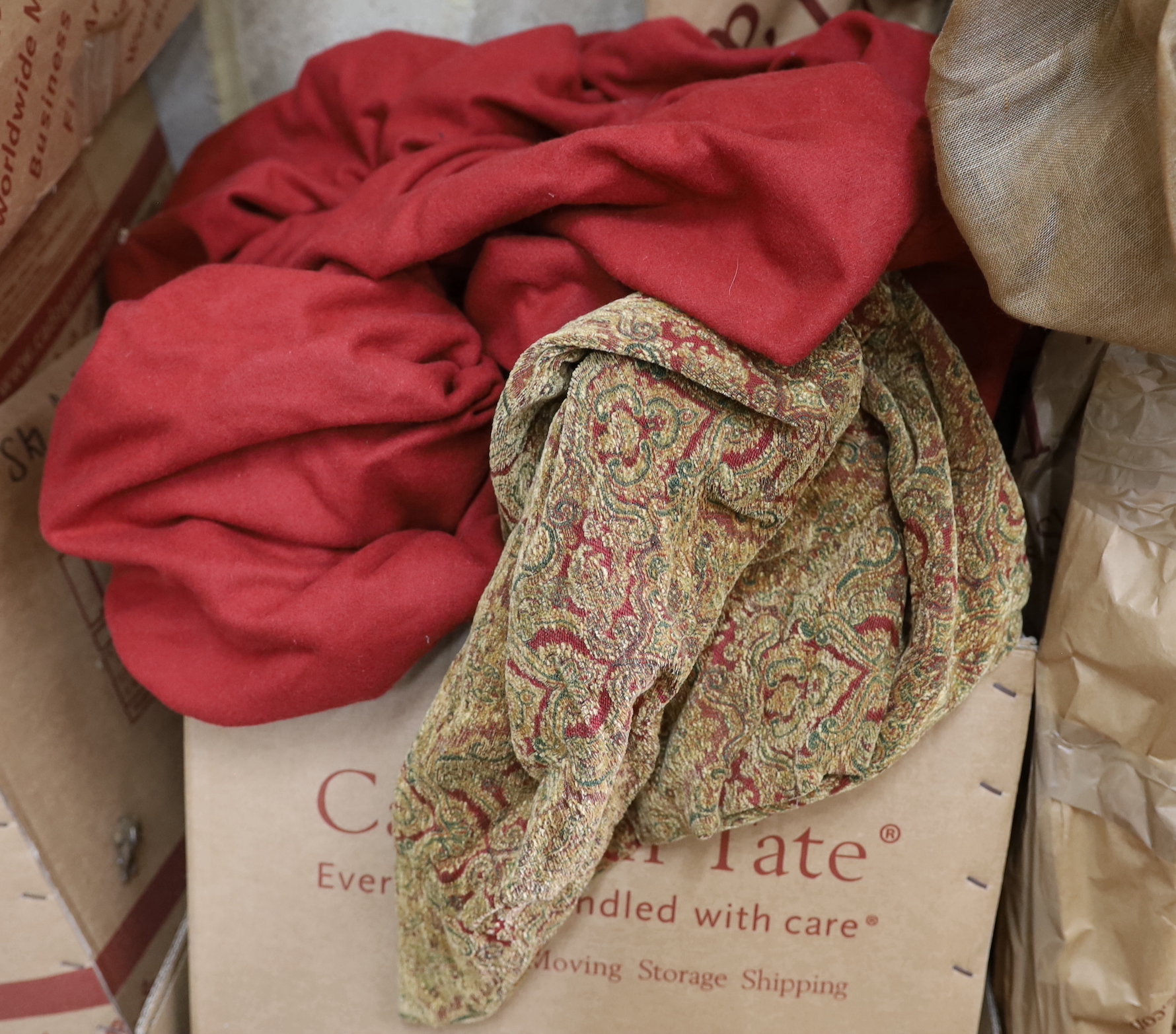 A quantity of aged metal curtain poles with woven leather tie backs and a large quantity of patterned red fabric curtains